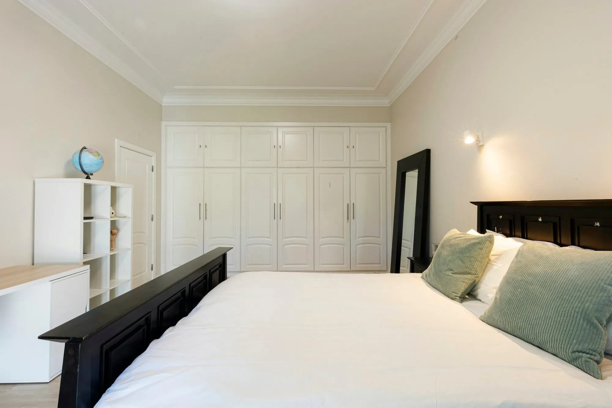 Bedroom with a white floor-to-ceiling fitted wardrobe under period cornicing